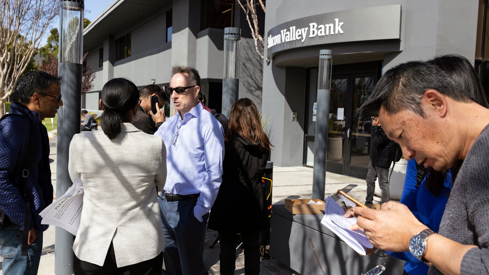 FDIC member Dedra Dorn (center left) speaks with individuals in line outside Silicon Valley Bank's headquarters in Santa Clara, Calif., on Monday, March 13, 2023. Photo by AP.