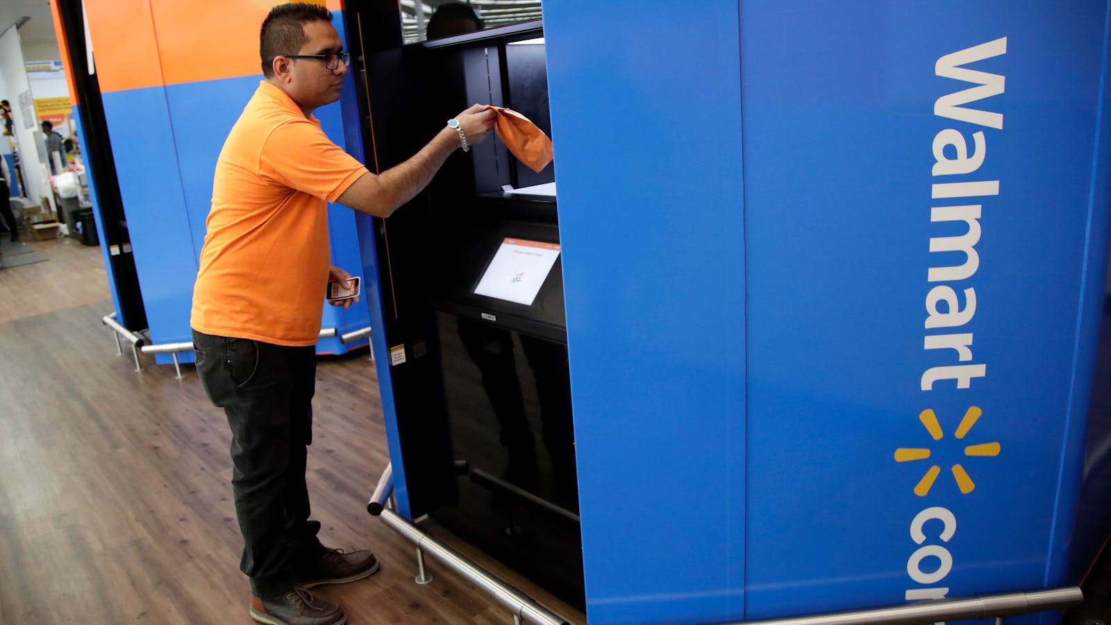 A Walmart manager demonstrating how customers can pick up online orders. Photo by AP