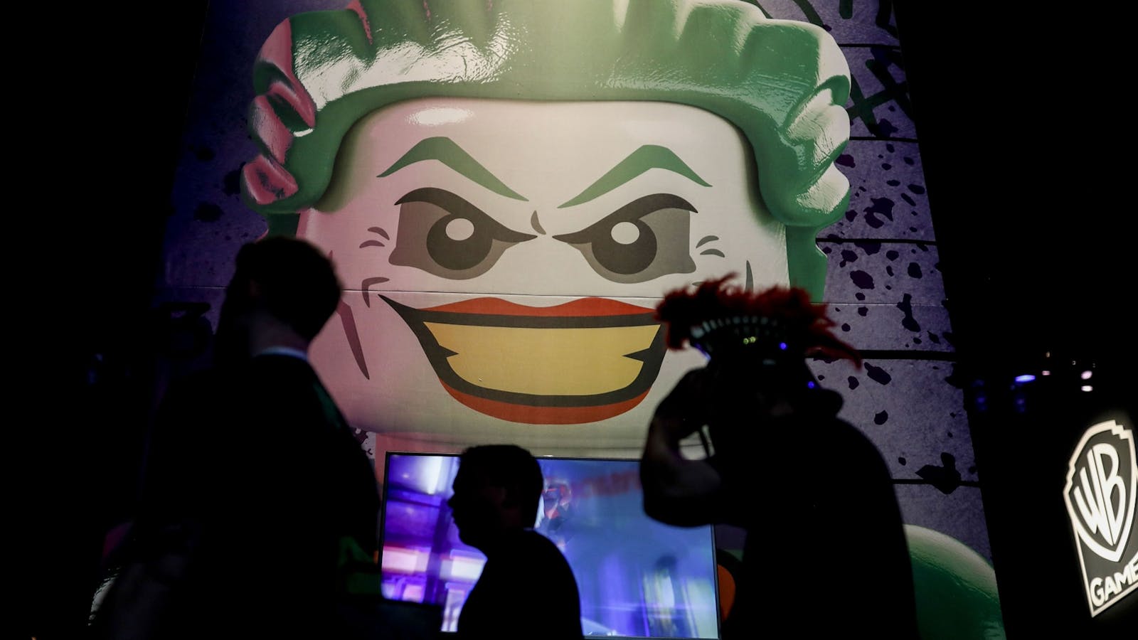 Attendees at the 2018 E3 conference in Los Angeles walk past a booth for Warner Bros. Interactive Entertainment. Photo by Bloomberg