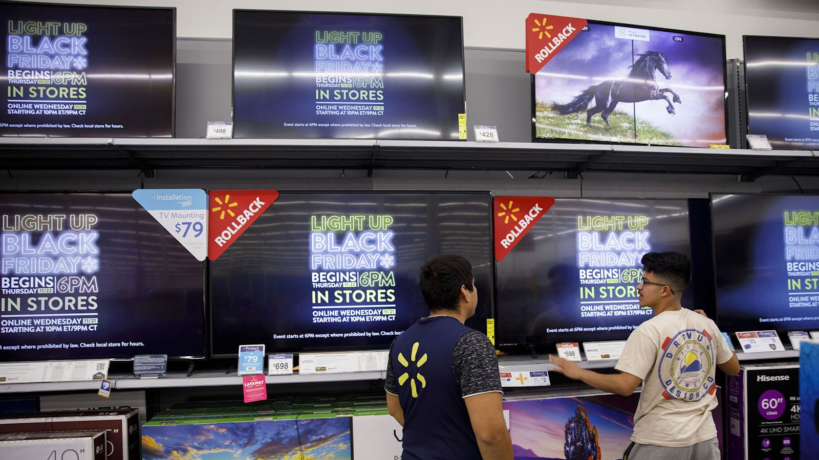 An employee assists a customer with televisions at a Walmart. Photo by Bloomberg