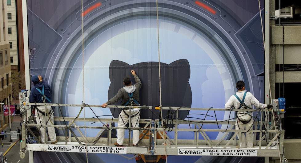 Workers install a billboard for GitHub. Photo by Bloomberg.