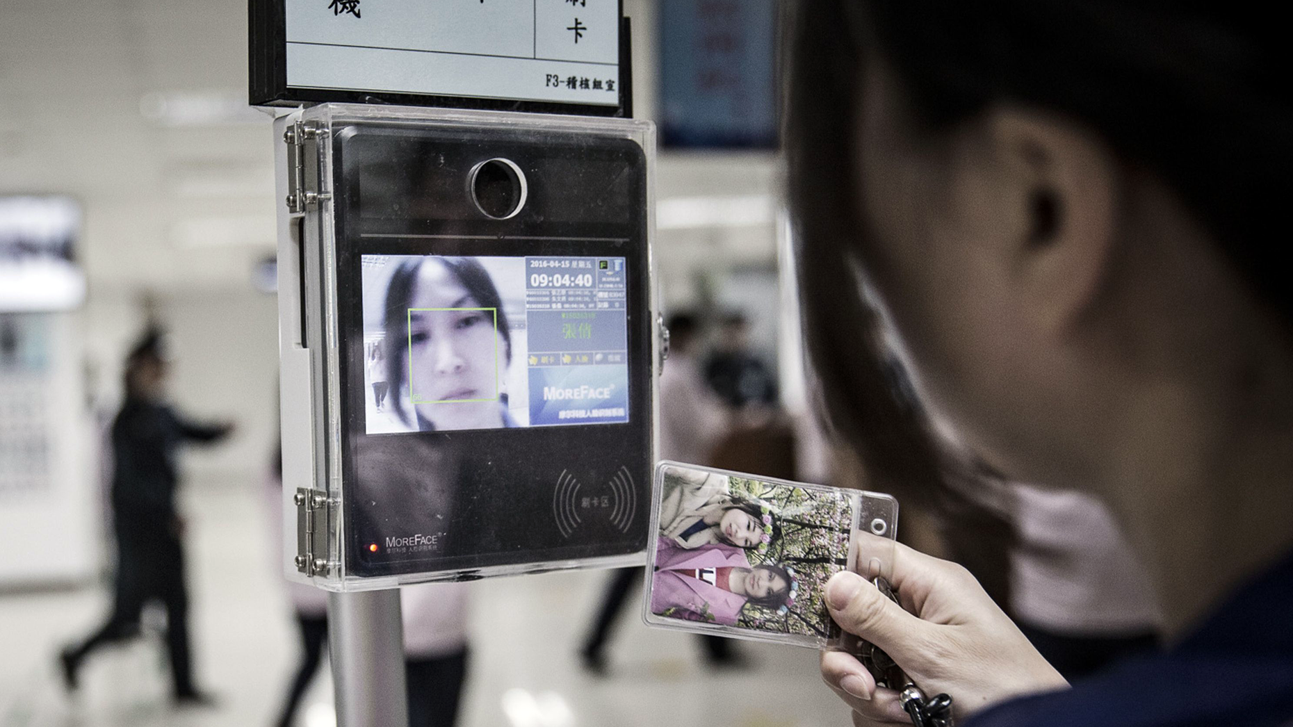 An employee uses a facial recognition device as she swipes her badge to enter the assembly line area at a Pegatron factory in Shanghai in 2016. Photo by Bloomberg.