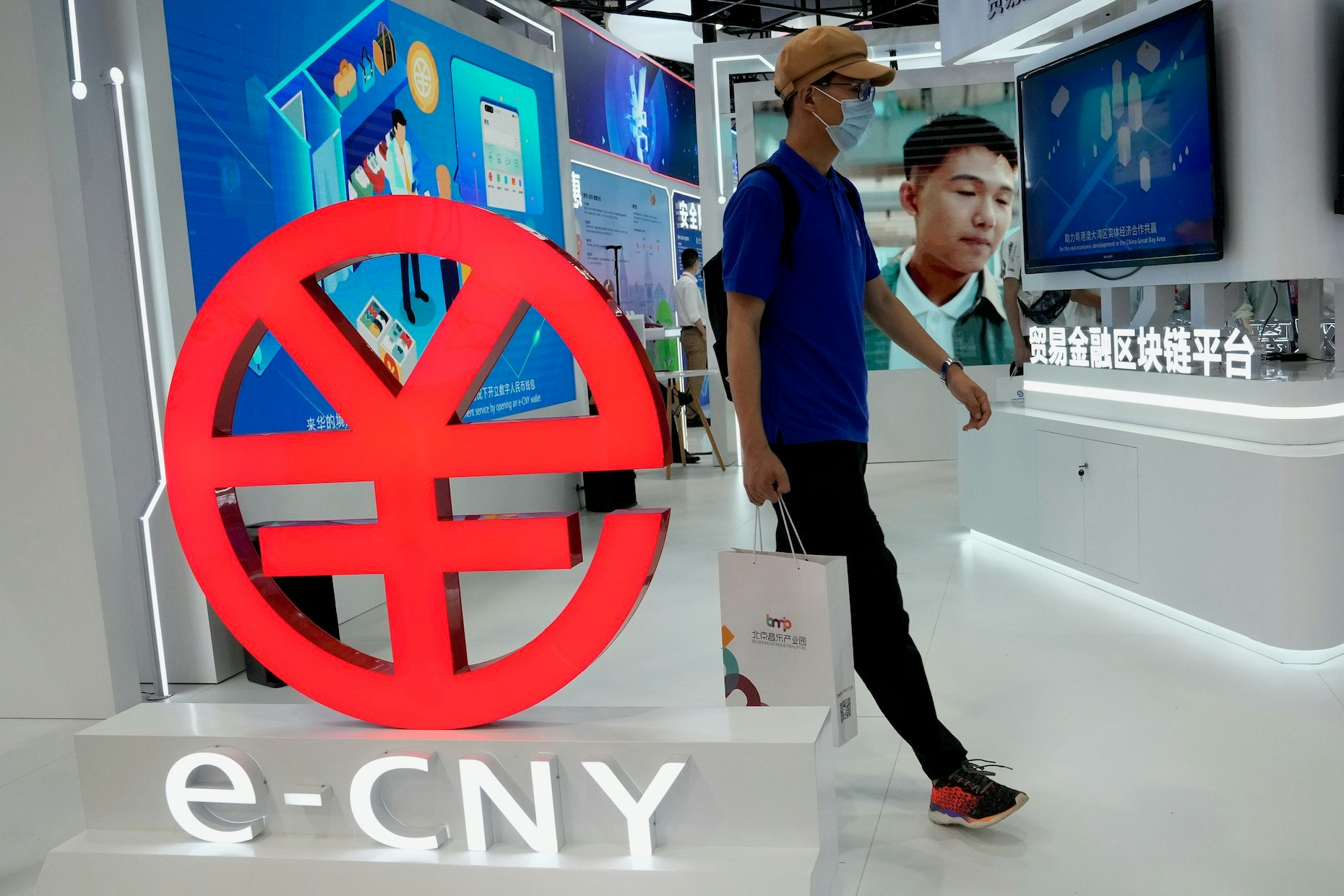 A visitor passes by a logo for the e-CNY, a digital version of the Chinese Yuan, displayed during a trade fair in Beijing on Sunday, Sept. 5. Photo: AP