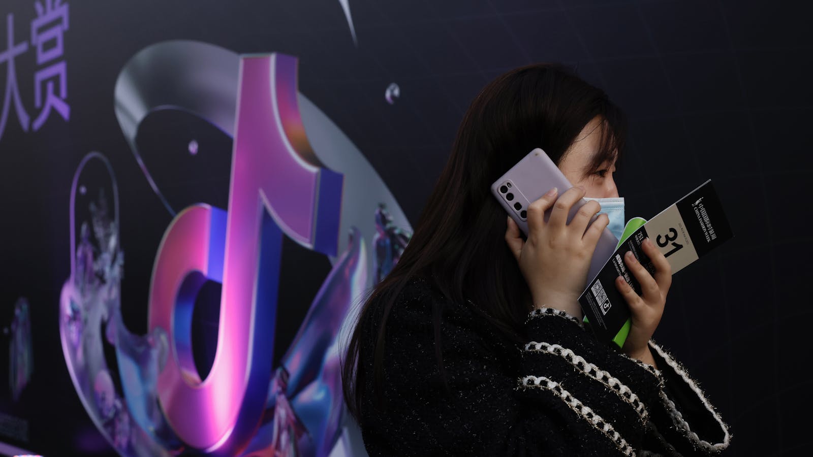 A woman talking on her phone near the logo for ByteDance's short-video app Douyin, where ad rates are particularly high. Photo by AP
