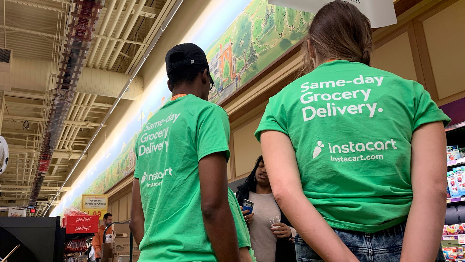 Workers from Instacart, the same-day grocery delivery service, receive instructions at a grocery store. Photo by AP.