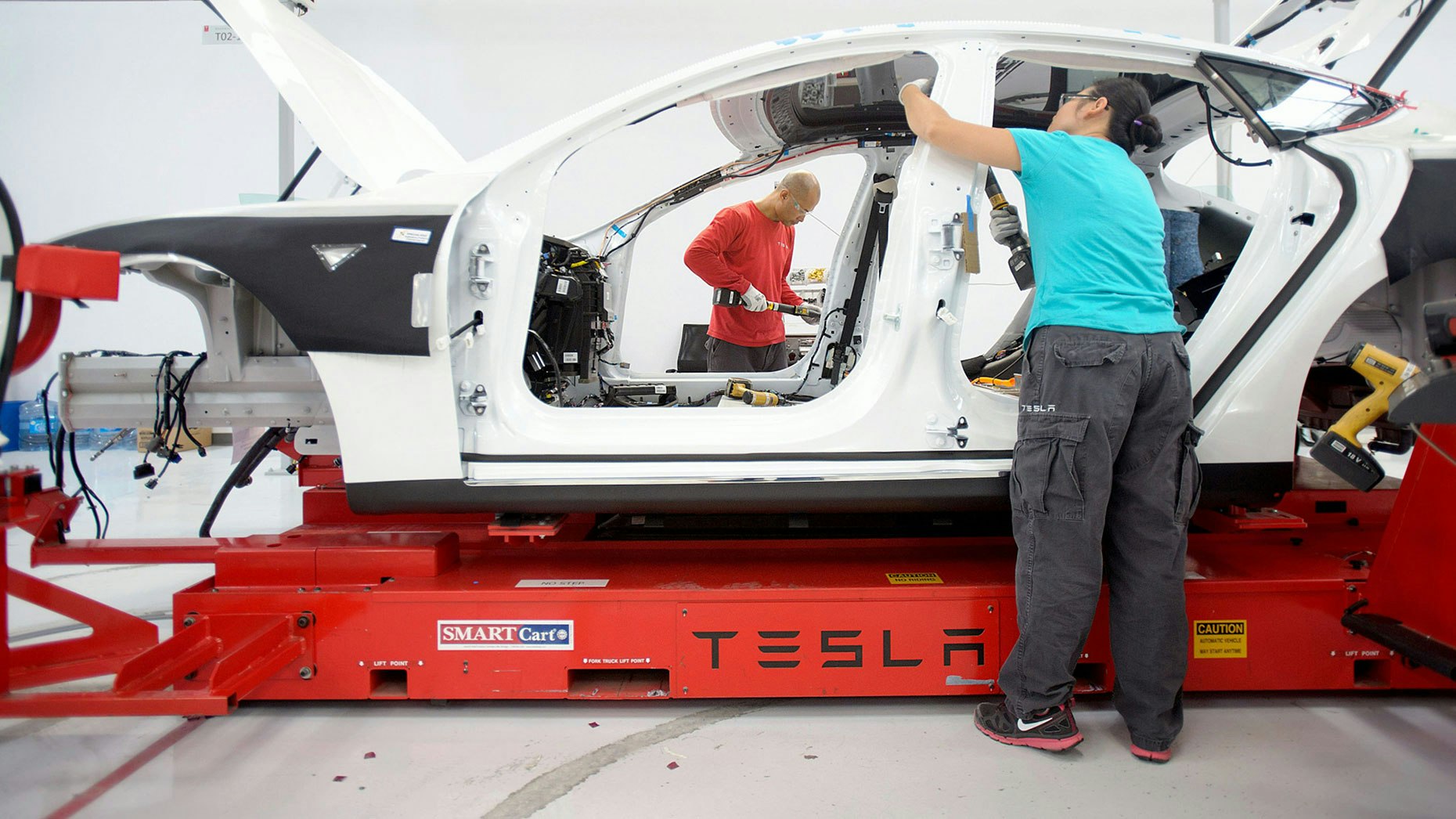 Tesla employees assembling a car. Photo by Bloomberg.