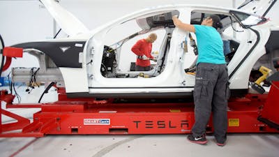 Tesla employees assembling a car. Photo by Bloomberg.