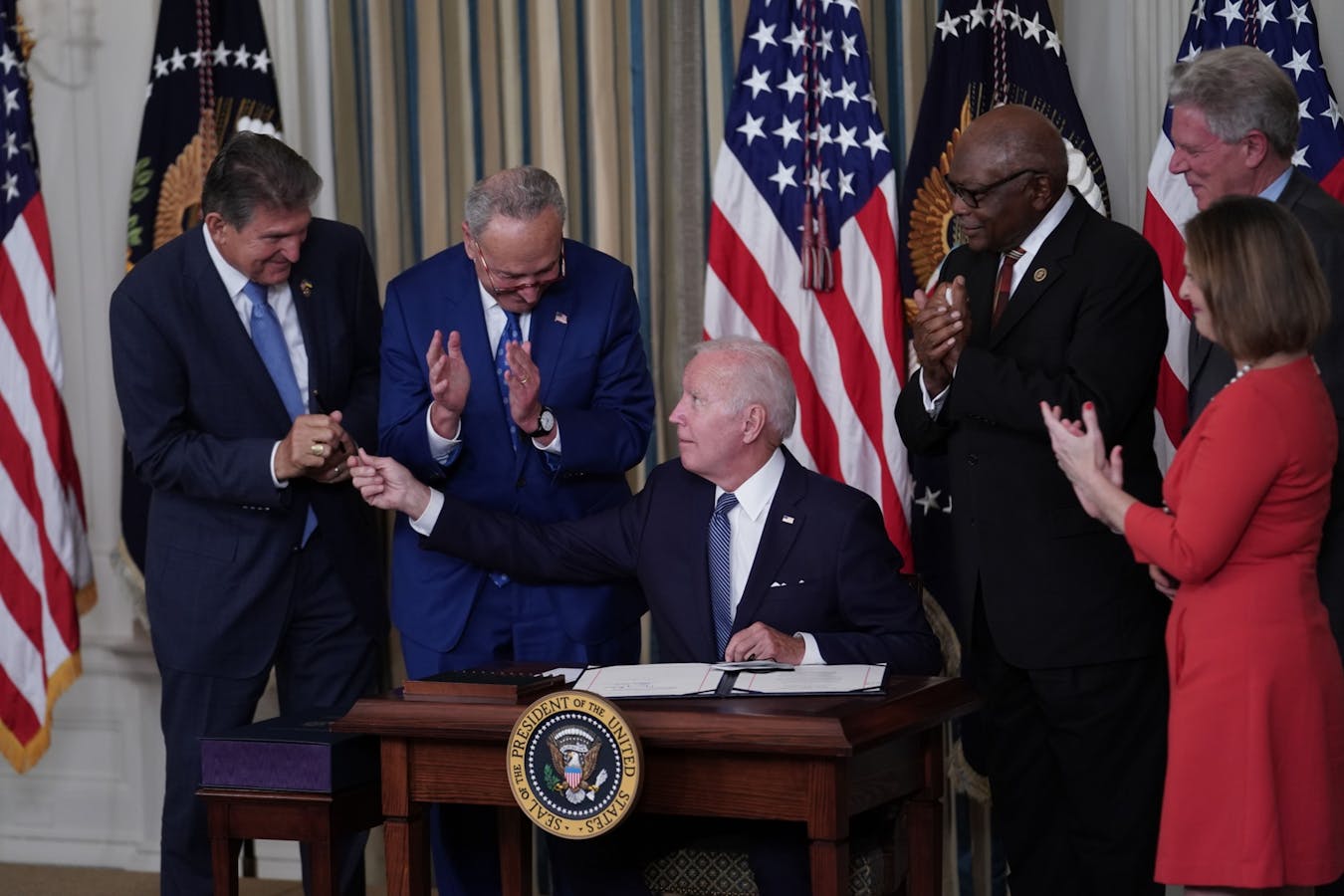 Biden signed the climate bill, containing about $100 billion for batteries, on Aug. 16. To his left, Sens. Joe Manchin and Chuck Schumer. Photo: Sarah Silbiger/Bloomberg